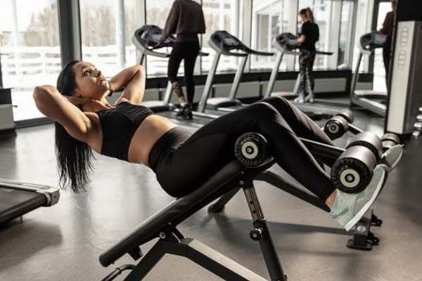 Woman performing sit ups on gym equipment.