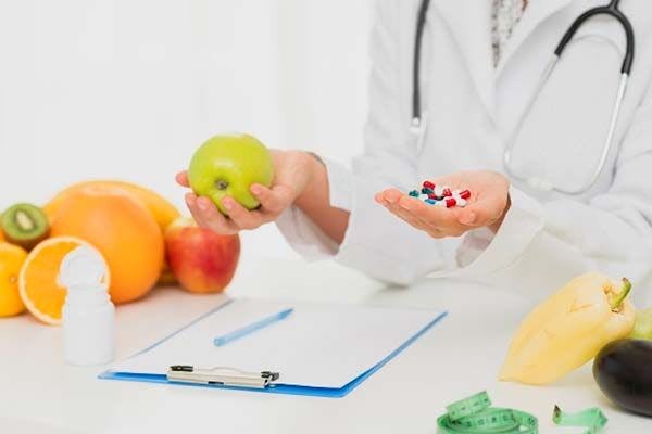 A scientist weighing up the differences between the vitamins in an apple and vitamins in pill form.